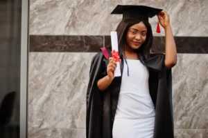 University of Alabama student posing for a photo with her graduation wears and result in her hand.