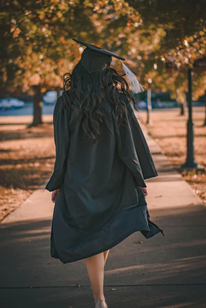 A South Dakota State University graduand and beneficiary of the Richard Wolles Scholarship program wearing are graduation gown and cat walking in the walkway.